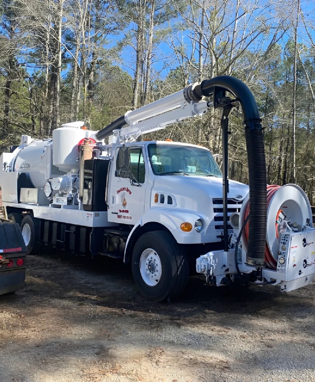 White utility truck with large hose attachment.